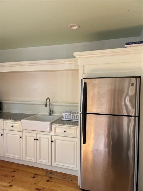 10 Orchard St Unit 8, Urbana, NY 14840 - kitchen with freestanding refrigerator, dark stone counters, white cabinetry, a sink, and light wood finished floors