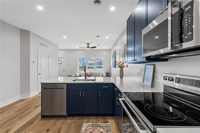 kitchen featuring a sink, blue cabinetry, a peninsula, appliances with stainless steel finishes, and visible vents