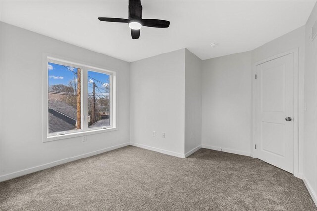 carpeted empty room featuring baseboards and ceiling fan