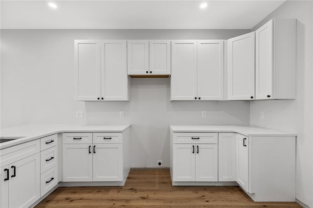 kitchen with white cabinets, wood finished floors, light countertops, and recessed lighting