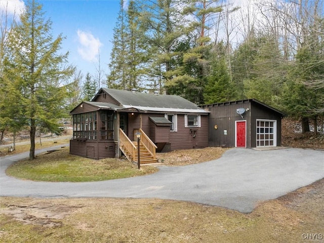 view of front facade with a sunroom and driveway