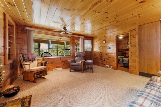 living area with carpet floors, visible vents, wood walls, and wooden ceiling