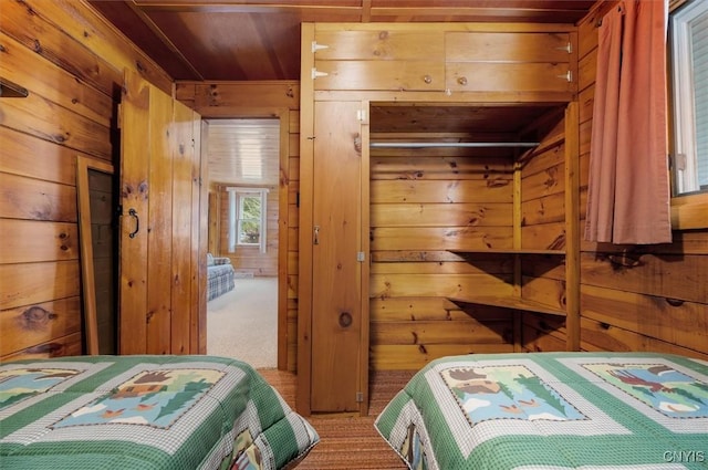 carpeted bedroom featuring wooden walls and wooden ceiling