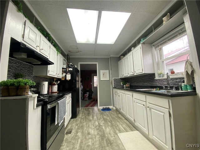 kitchen featuring white cabinets, a sink, stainless steel range with electric cooktop, light wood-style floors, and under cabinet range hood