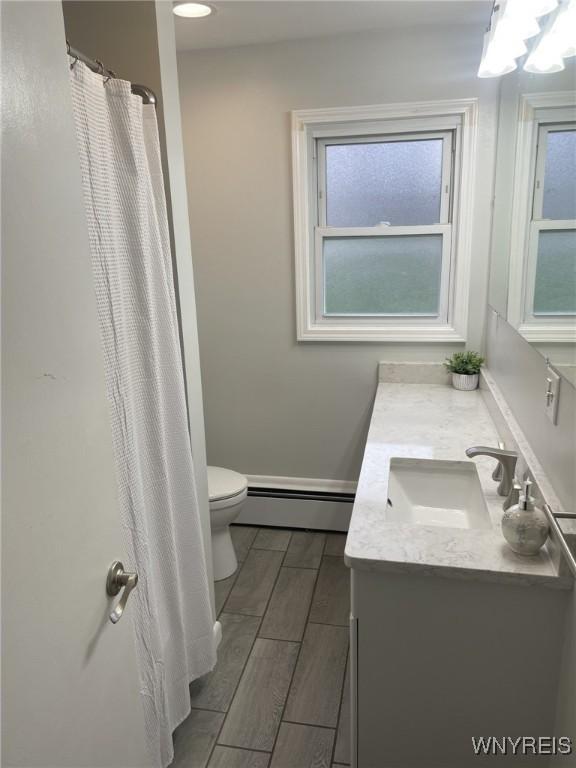 bathroom featuring a baseboard radiator, toilet, vanity, and wood tiled floor