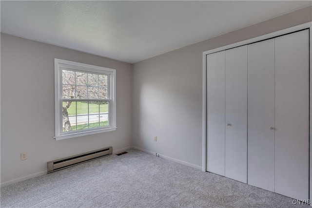 unfurnished bedroom featuring visible vents, baseboards, carpet, baseboard heating, and a closet