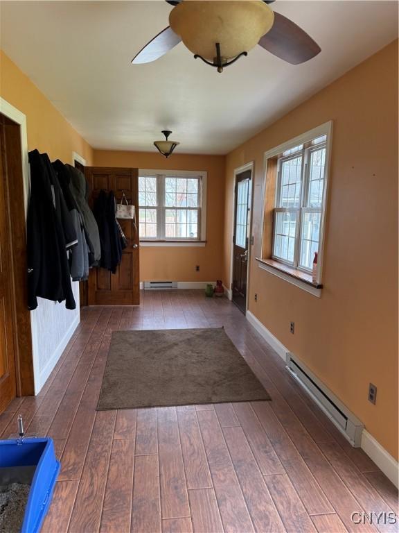 interior space featuring a baseboard heating unit, wood-type flooring, baseboards, a baseboard radiator, and ceiling fan