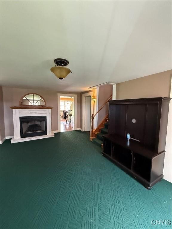 unfurnished living room featuring stairway, a glass covered fireplace, and carpet