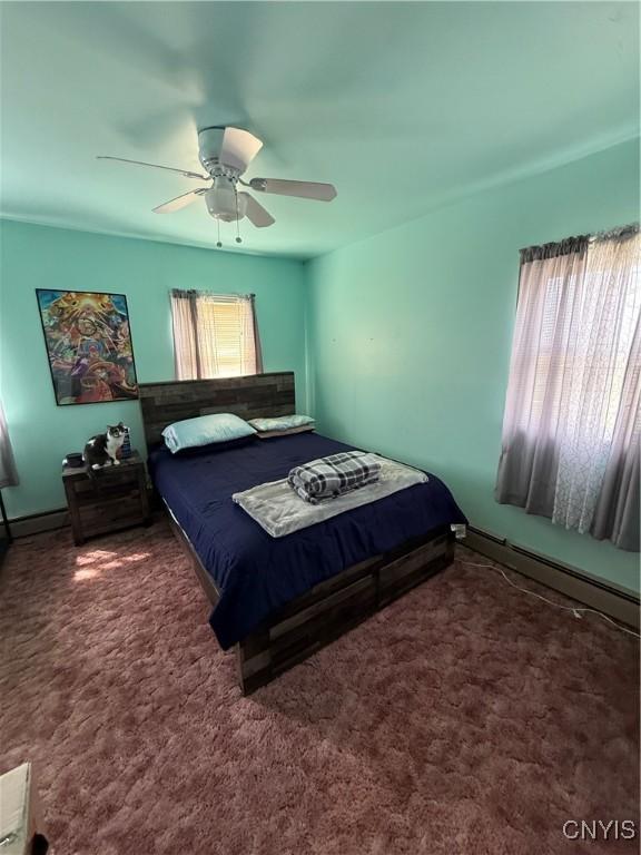 carpeted bedroom with ceiling fan, baseboards, and multiple windows