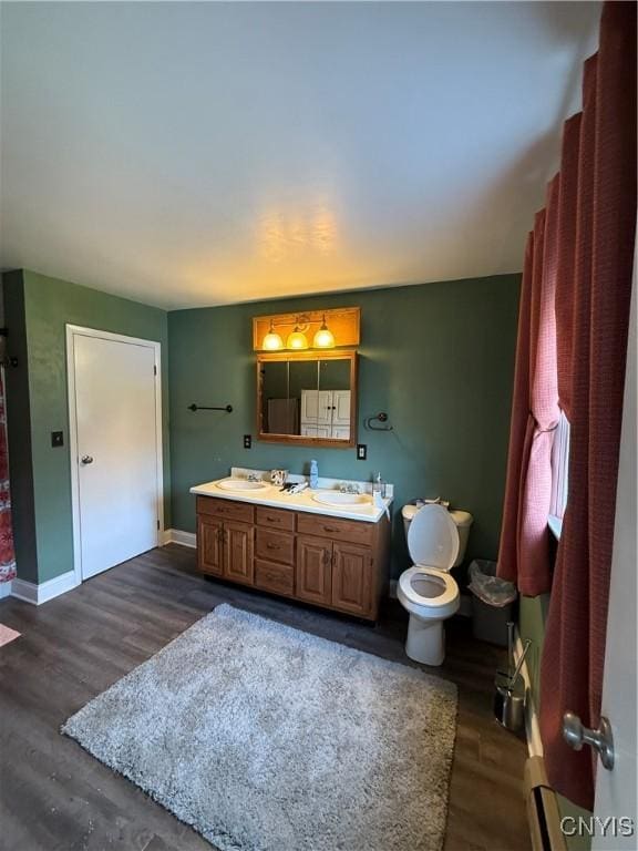 full bath with double vanity, toilet, wood finished floors, and a sink