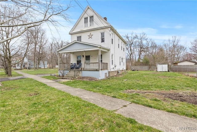 traditional style home featuring a front yard, a chimney, covered porch, and fence