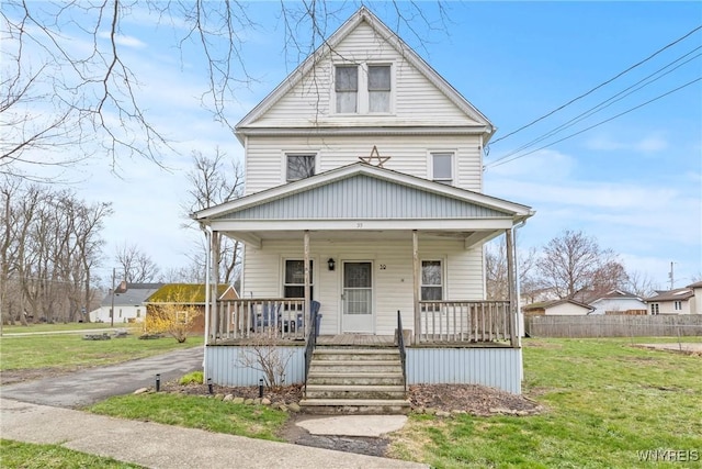 view of front of home with a front yard, covered porch, and fence