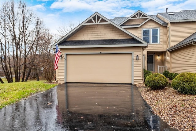 view of front of home with a shingled roof, aphalt driveway, and a garage
