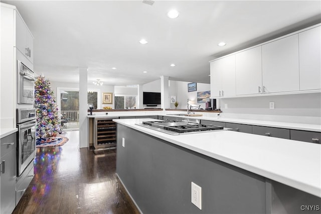 kitchen with recessed lighting, dark wood-style floors, wine cooler, light countertops, and appliances with stainless steel finishes