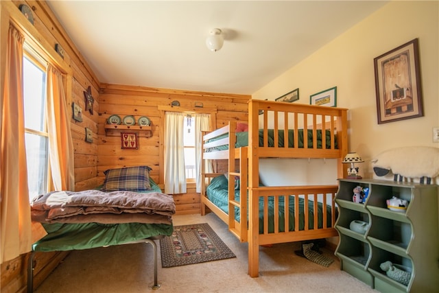 bedroom featuring carpet, wood walls, and multiple windows