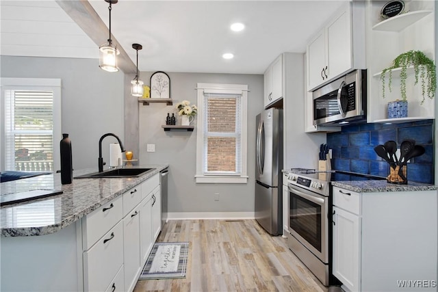 kitchen with a peninsula, open shelves, stainless steel appliances, and a sink