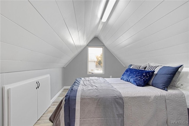 bedroom with wood finished floors and lofted ceiling