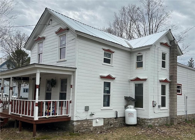 view of side of home featuring a porch and metal roof
