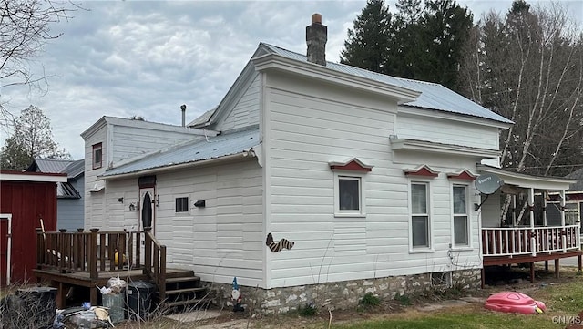 back of property with a chimney, a deck, and metal roof
