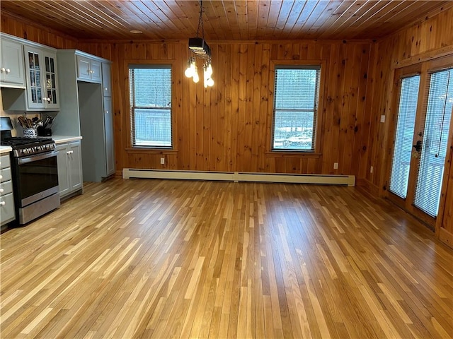 kitchen with light countertops, stainless steel range with gas stovetop, wood walls, and wood ceiling