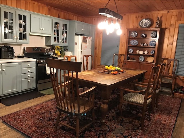 dining space with wood ceiling, wood finished floors, and wooden walls