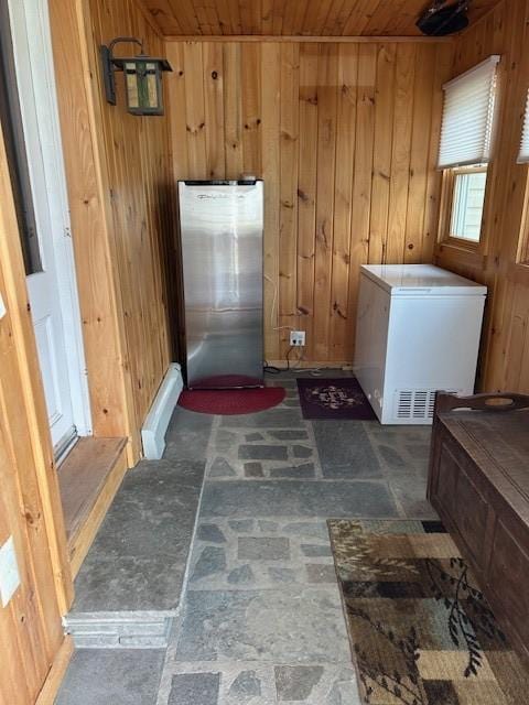 laundry room featuring wooden ceiling, wooden walls, and stone finish floor