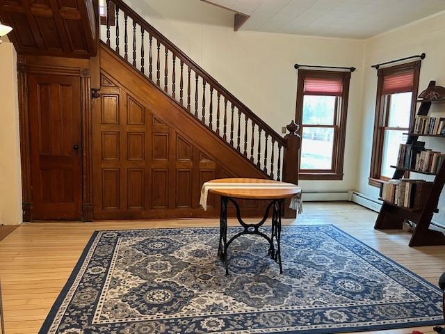 entrance foyer with a baseboard radiator, stairway, and light wood finished floors