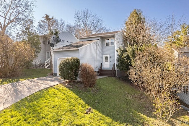 view of front of property featuring driveway, entry steps, a front yard, and a garage