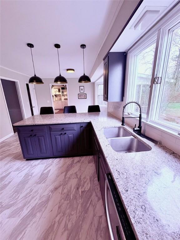 kitchen featuring marble finish floor, a sink, decorative light fixtures, light stone countertops, and a peninsula