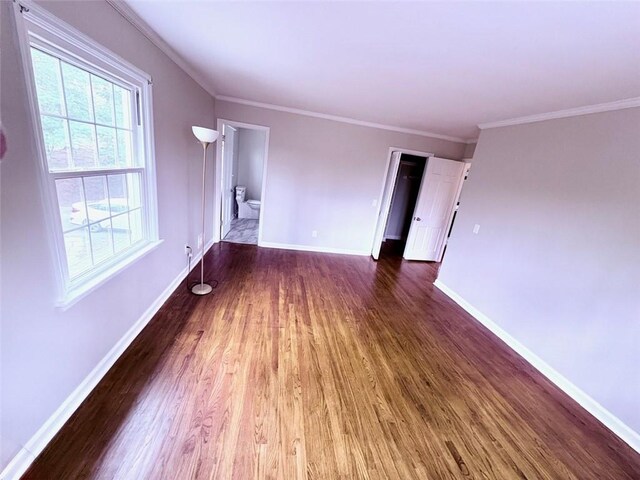 unfurnished living room featuring baseboards, wood finished floors, and crown molding