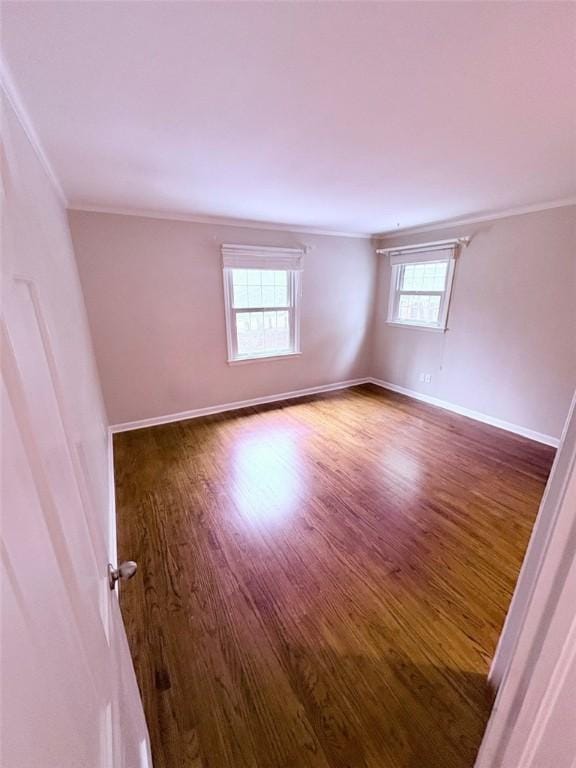 spare room with wood finished floors, baseboards, and ornamental molding