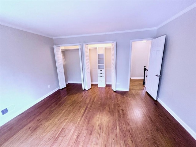 unfurnished bedroom with baseboards, multiple closets, and wood finished floors