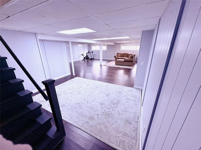 interior space with a paneled ceiling, baseboards, and dark wood-style flooring