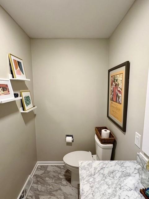 bathroom featuring marble finish floor, toilet, visible vents, and baseboards