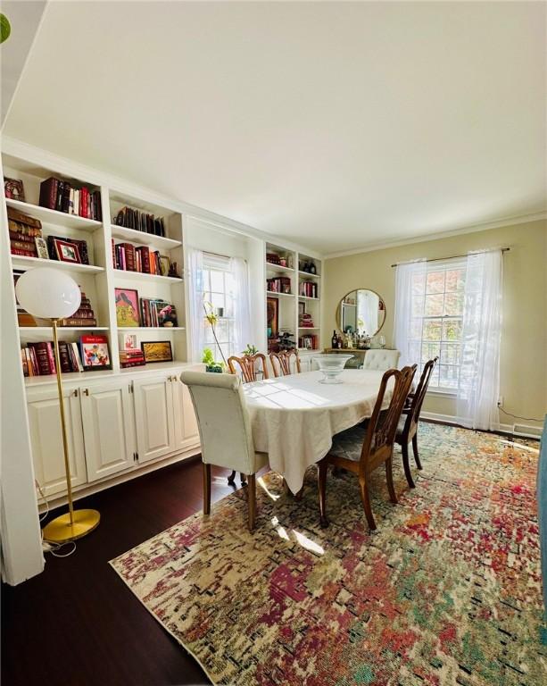 dining area with plenty of natural light, dark wood-style floors, built in features, and ornamental molding