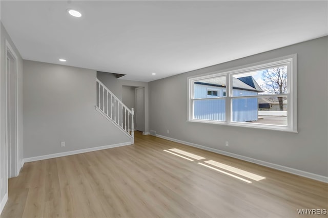 unfurnished living room featuring stairway, baseboards, recessed lighting, and light wood-type flooring