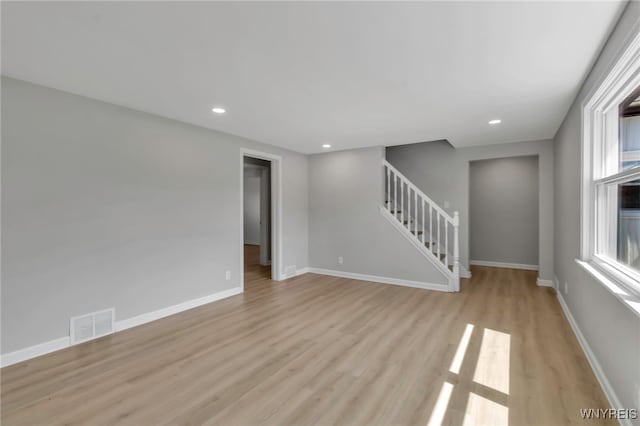 unfurnished living room featuring baseboards, visible vents, light wood finished floors, and stairs