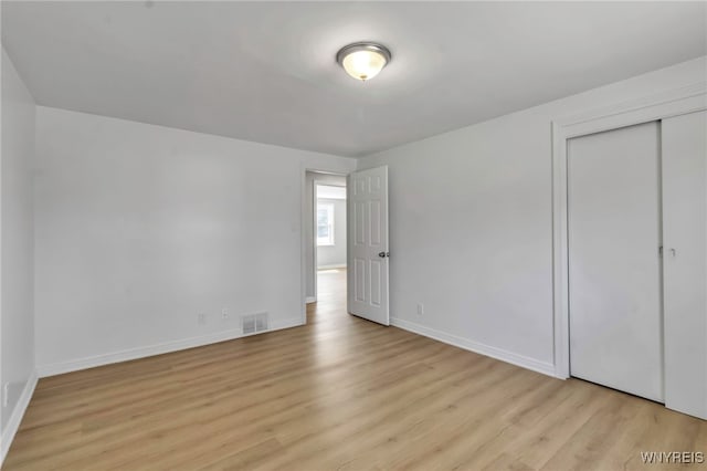 unfurnished bedroom featuring a closet, light wood-type flooring, visible vents, and baseboards