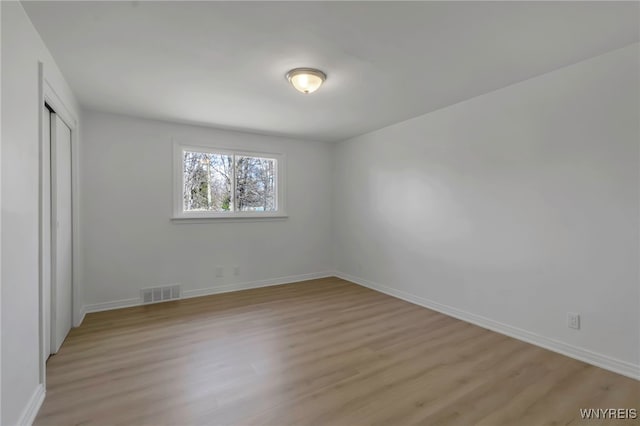 unfurnished bedroom with a closet, light wood-style flooring, visible vents, and baseboards