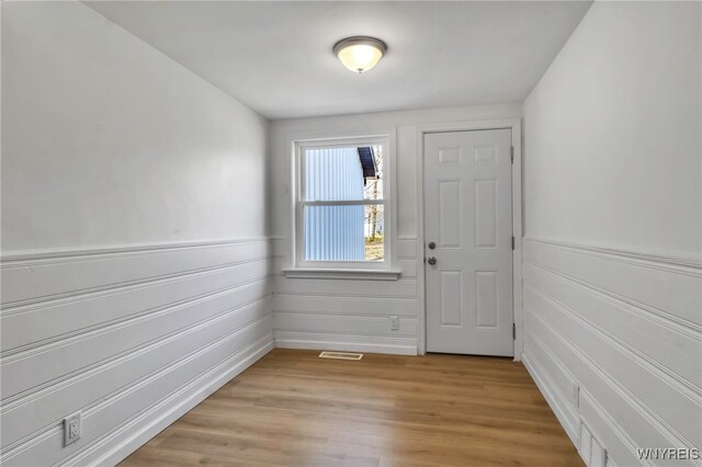 doorway featuring a wainscoted wall, light wood-style floors, and visible vents