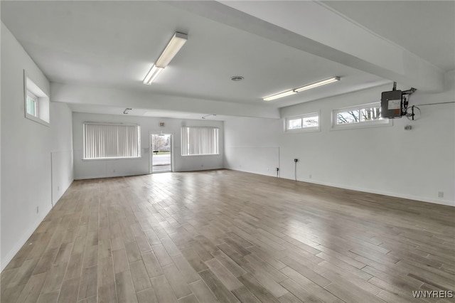 empty room featuring a wealth of natural light, wood finished floors, and baseboards