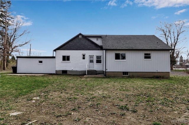 rear view of property with a yard, a shingled roof, and entry steps