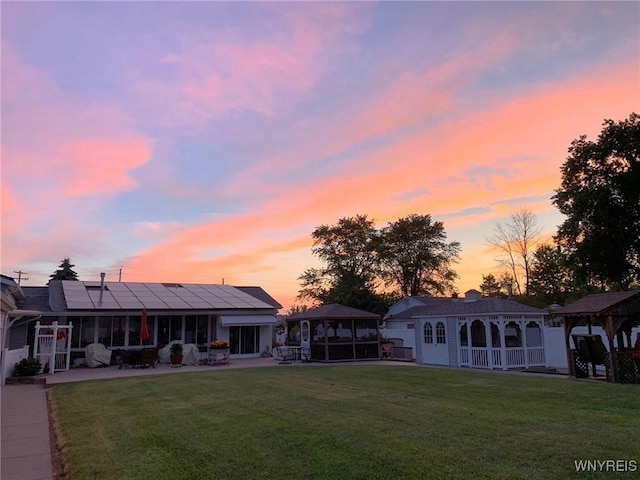 back of property with roof mounted solar panels, a lawn, a gazebo, and a patio