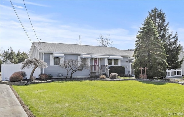 view of front of house featuring roof with shingles, a front yard, and fence