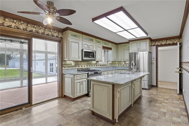 kitchen with stone finish floor, appliances with stainless steel finishes, and cream cabinets