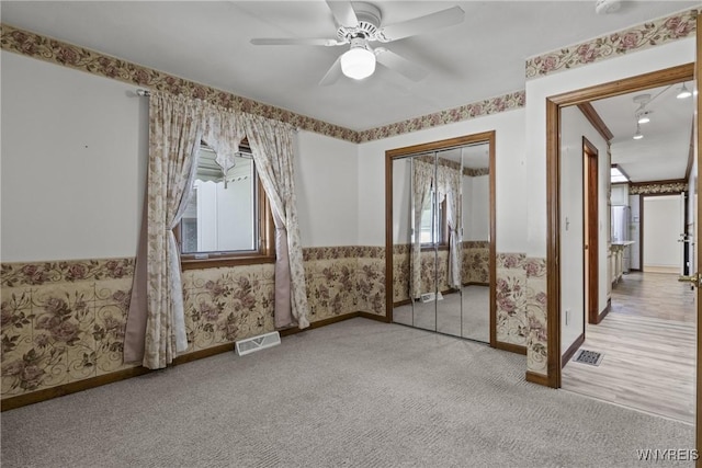 interior space featuring wallpapered walls, visible vents, a ceiling fan, and baseboards