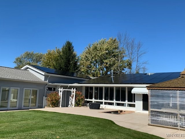 back of house featuring solar panels, a sunroom, a yard, and a patio