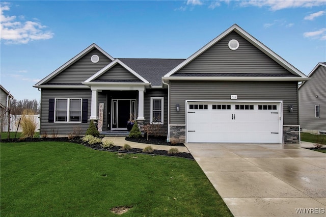 view of front of house featuring an attached garage, driveway, stone siding, and a front yard