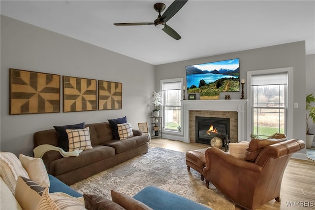 living room with a fireplace, light wood-style flooring, and a ceiling fan