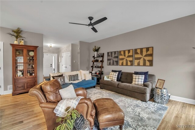 living area featuring light wood-style floors, a ceiling fan, and baseboards